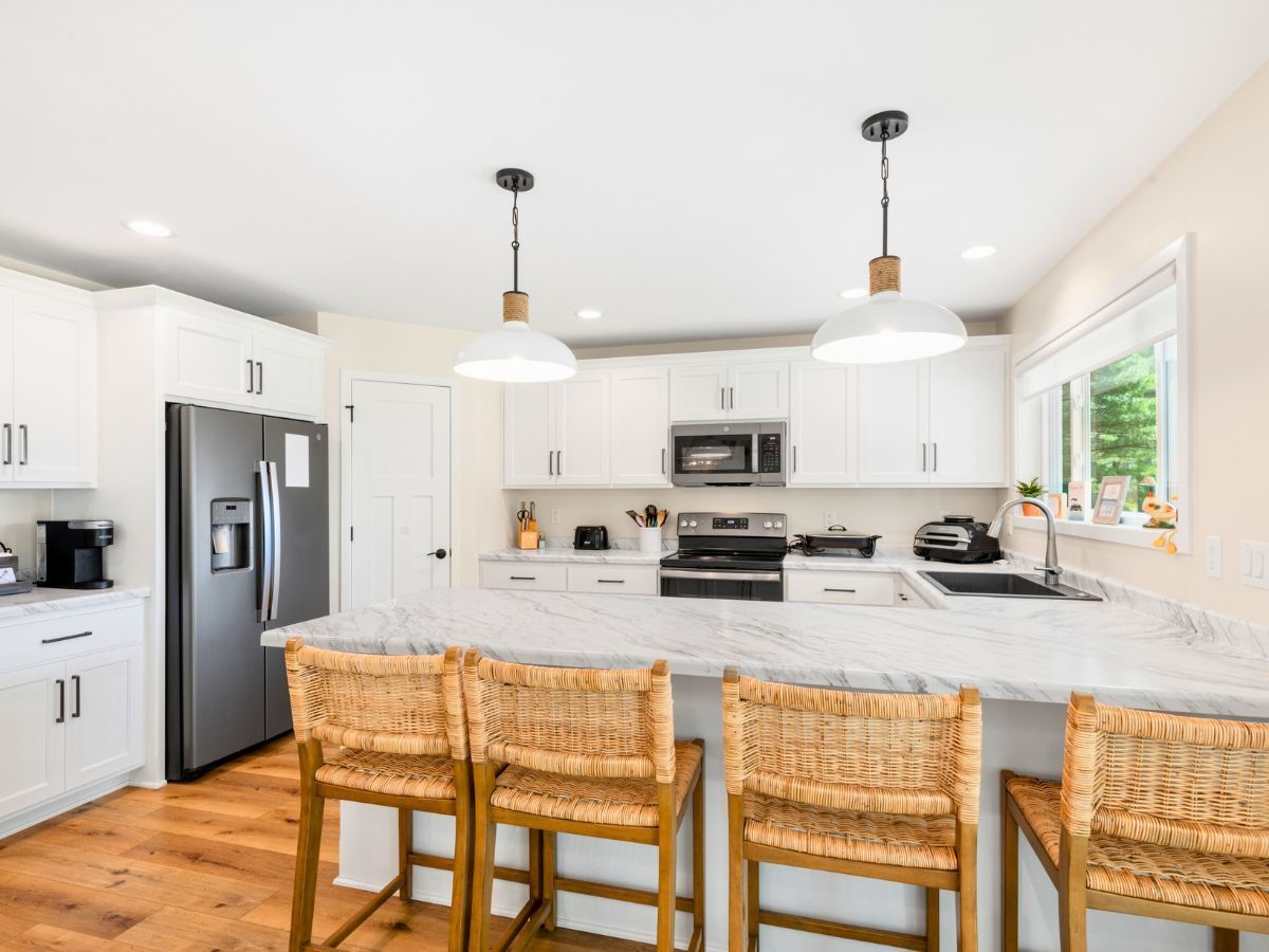 A kitchen with white cabinets and wicker chairs