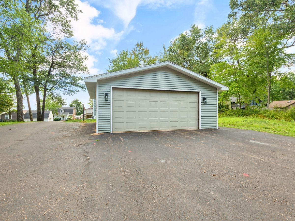 A white garage with a driveway and trees in the background