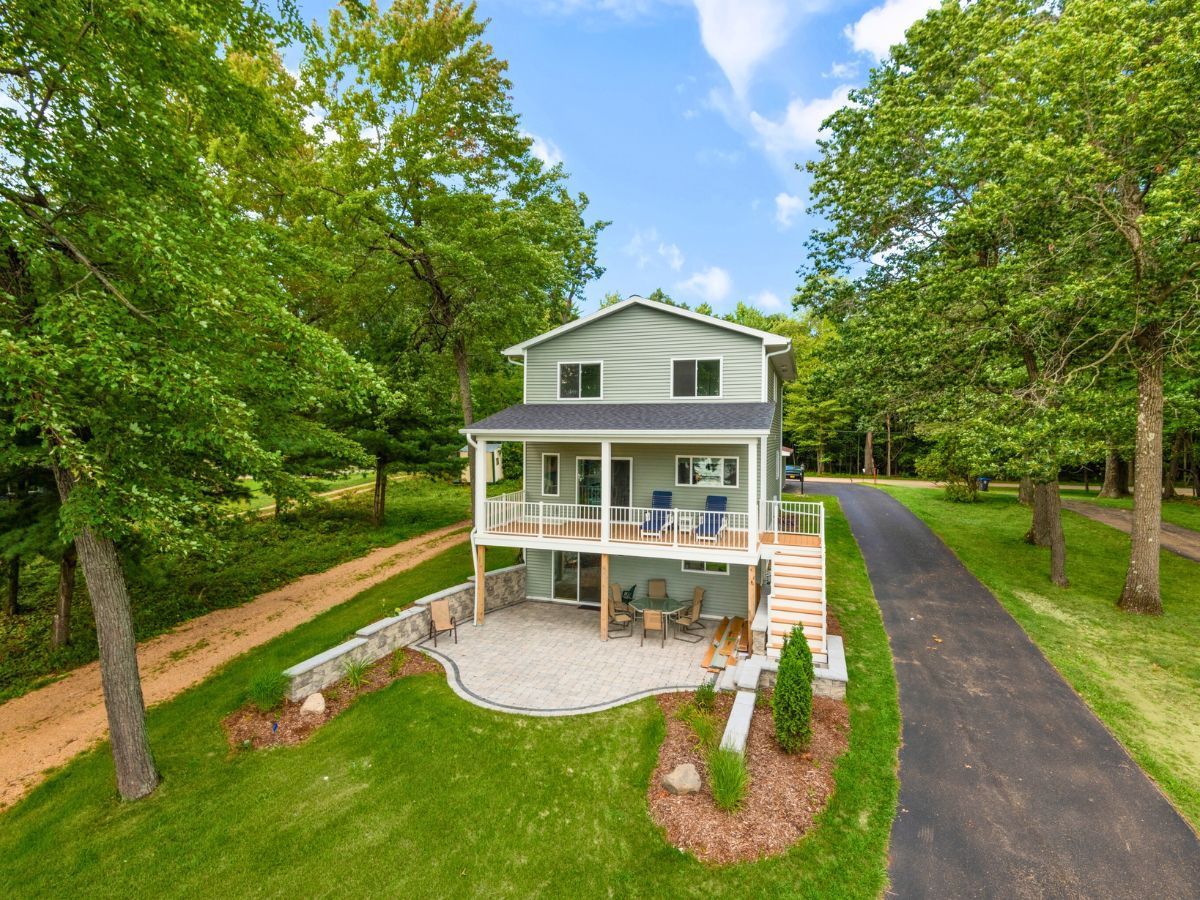 An aerial view of a house with a driveway leading to it surrounded by trees.