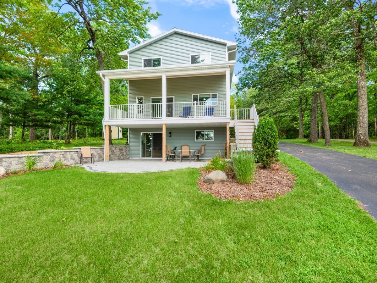 A large white house with a large lawn in front of it surrounded by trees.
