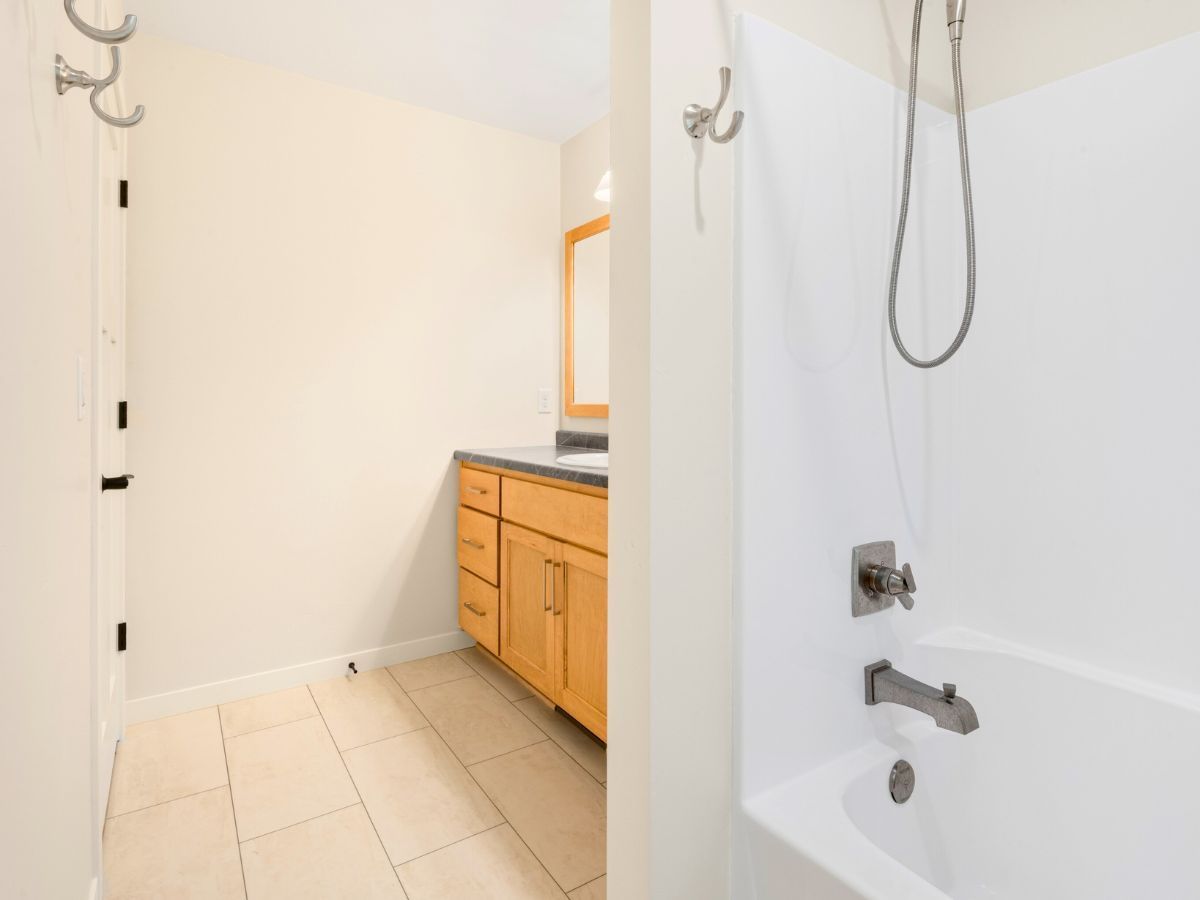A bathroom with a tub , sink , mirror and shower.