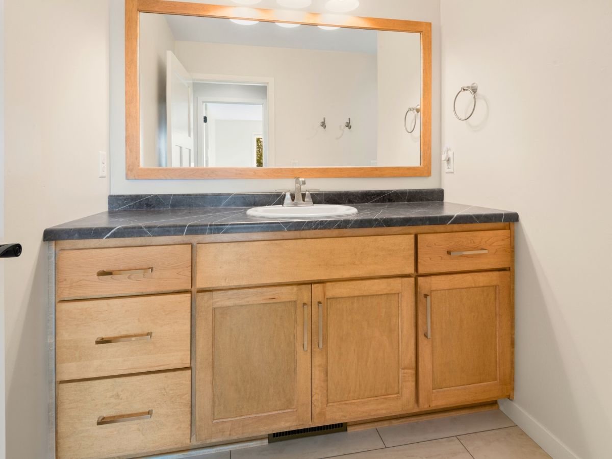 A bathroom with a sink , mirror and wooden cabinets