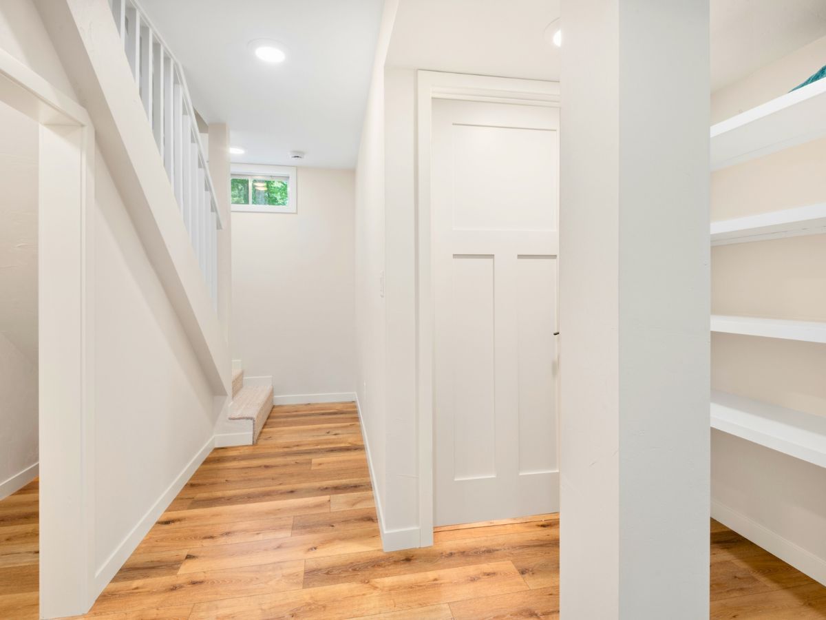 A hallway with hardwood floors and white walls in a house.