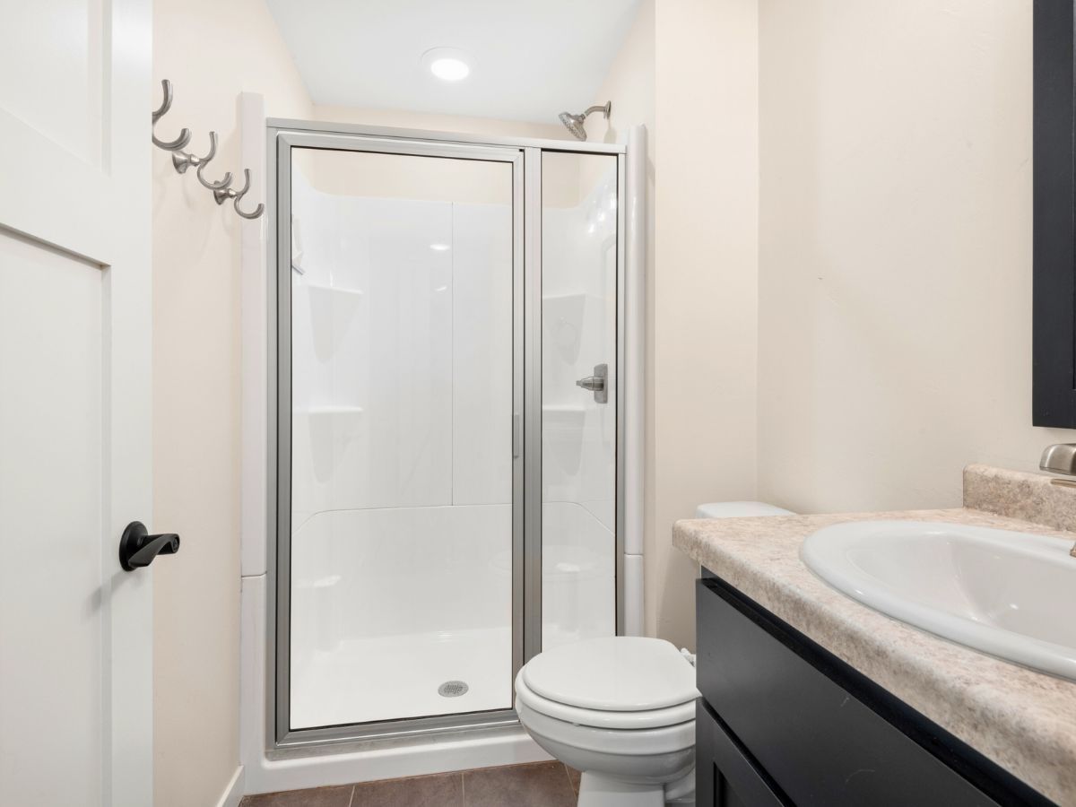 A bathroom with a toilet , sink and shower.