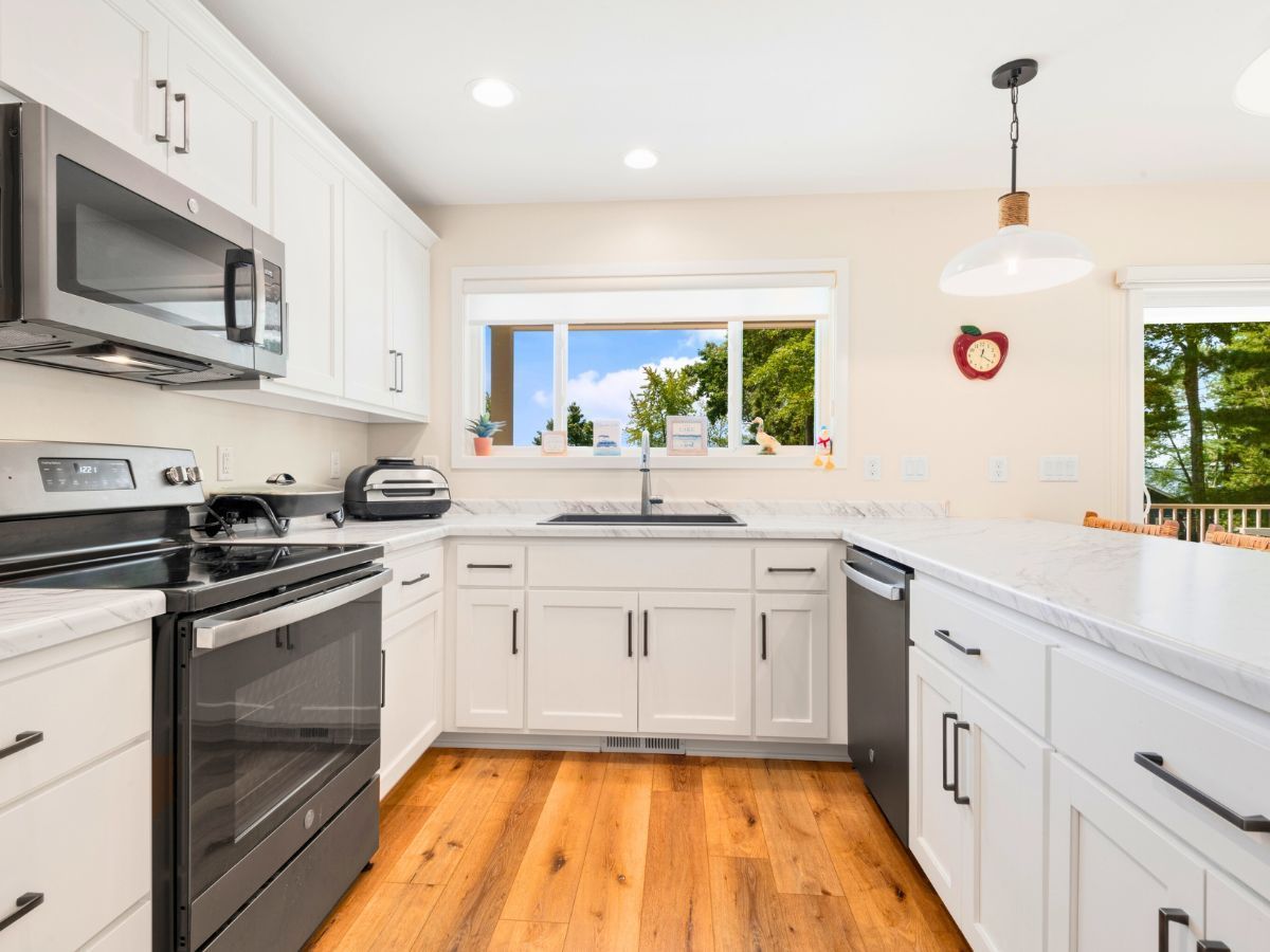 A kitchen with white cabinets , stainless steel appliances , and hardwood floors.