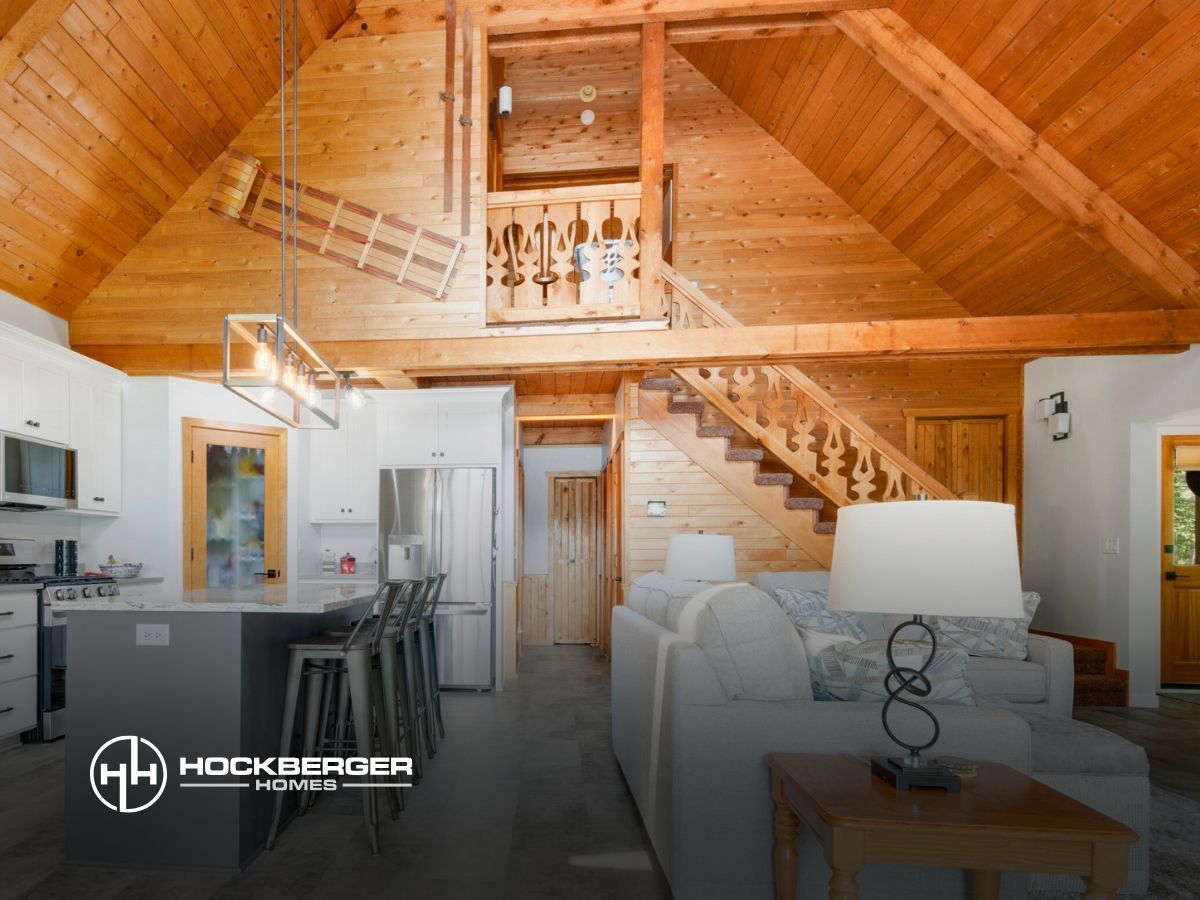 A living room and kitchen in a log cabin with a wooden staircase.