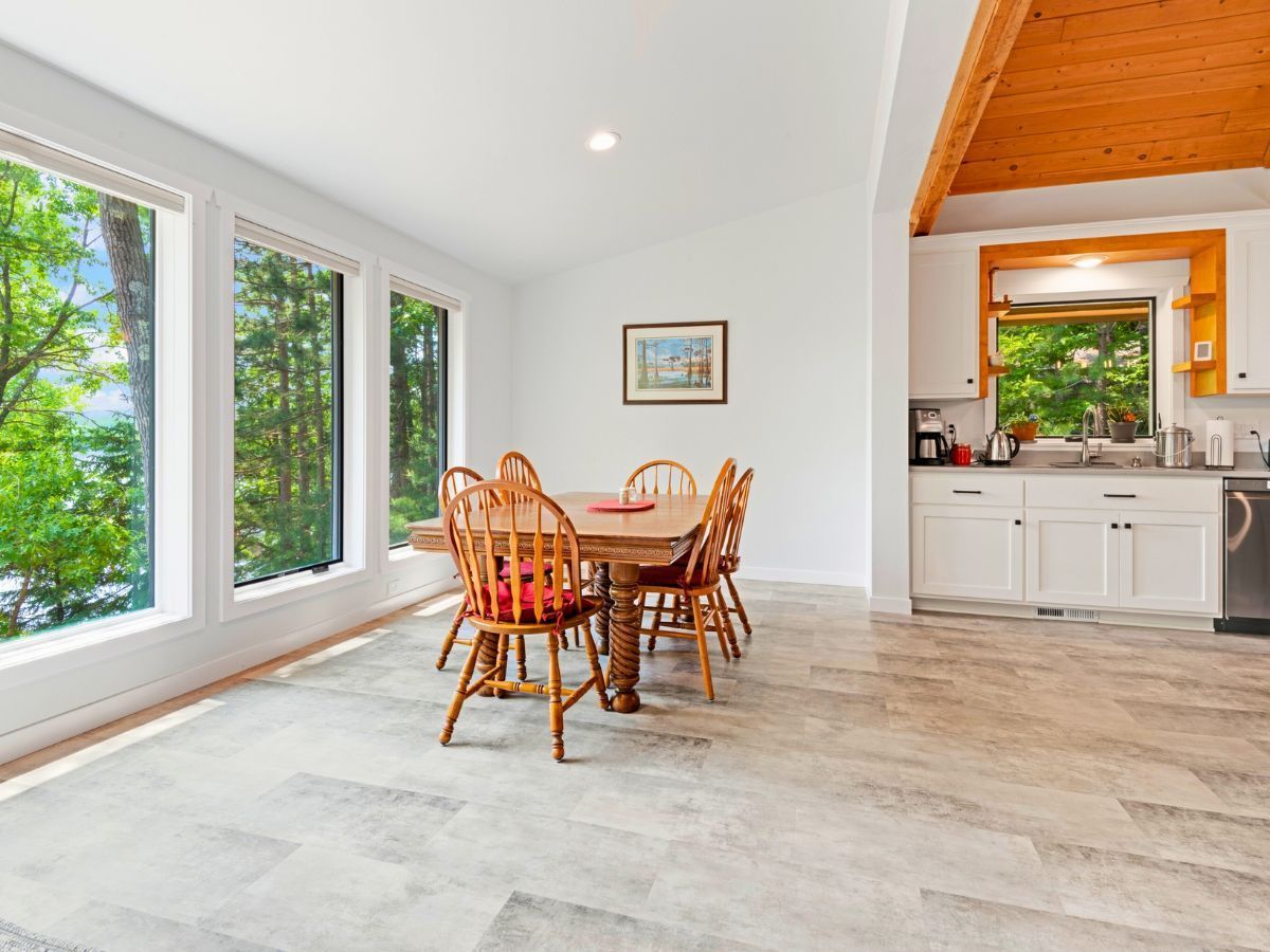 A dining room with a table and chairs and a kitchen.