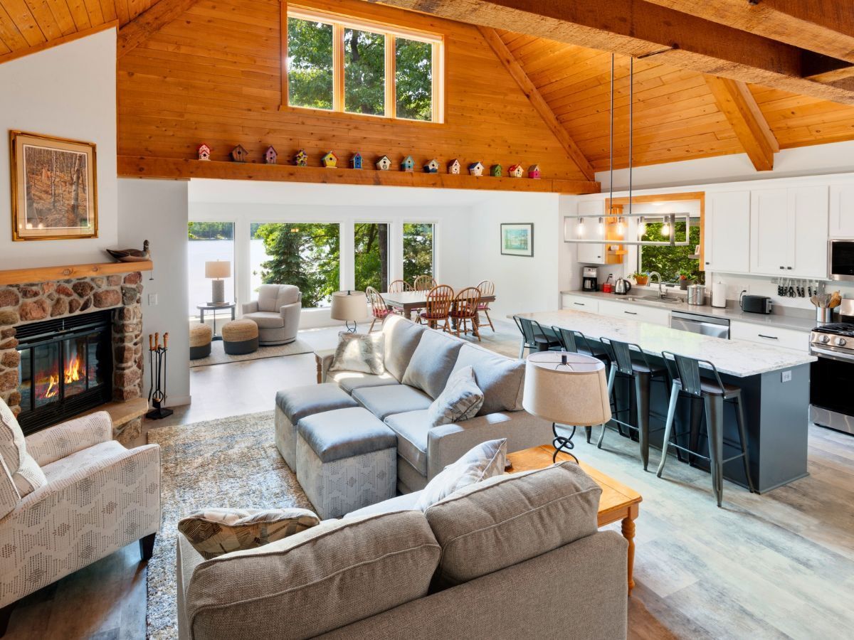 A living room with a couch , chairs , a fireplace and a kitchen.