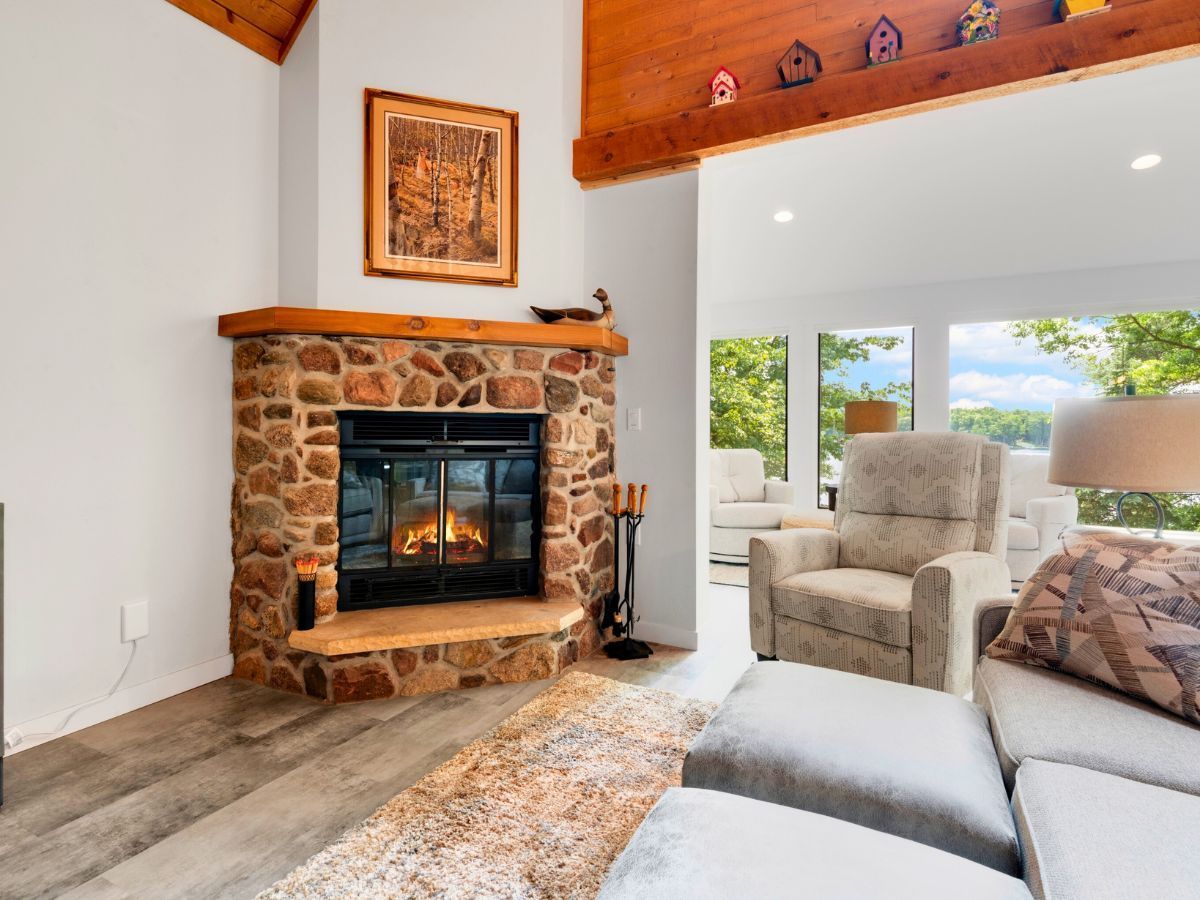 A living room with a stone fireplace , couch , chair and ottoman.