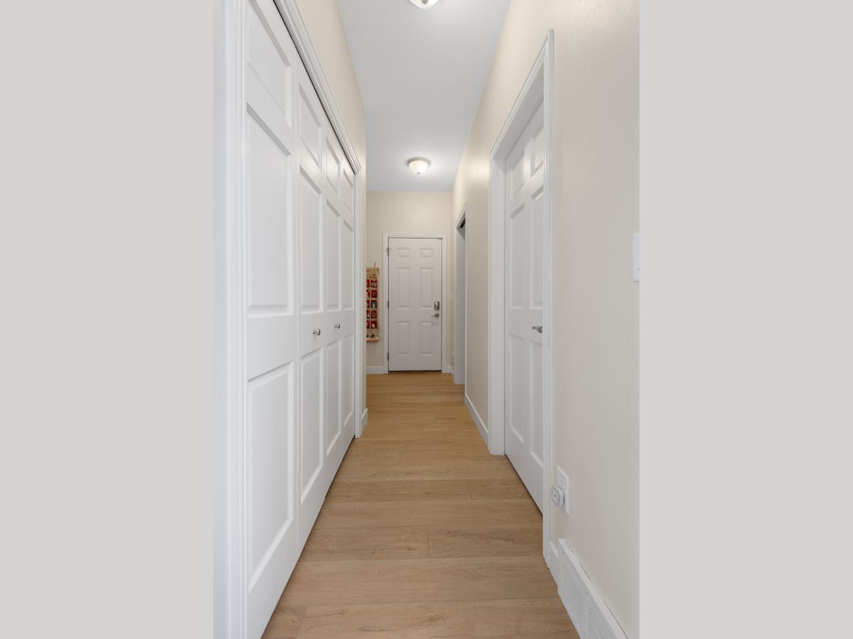 A long hallway with white walls and wooden floors in a house.