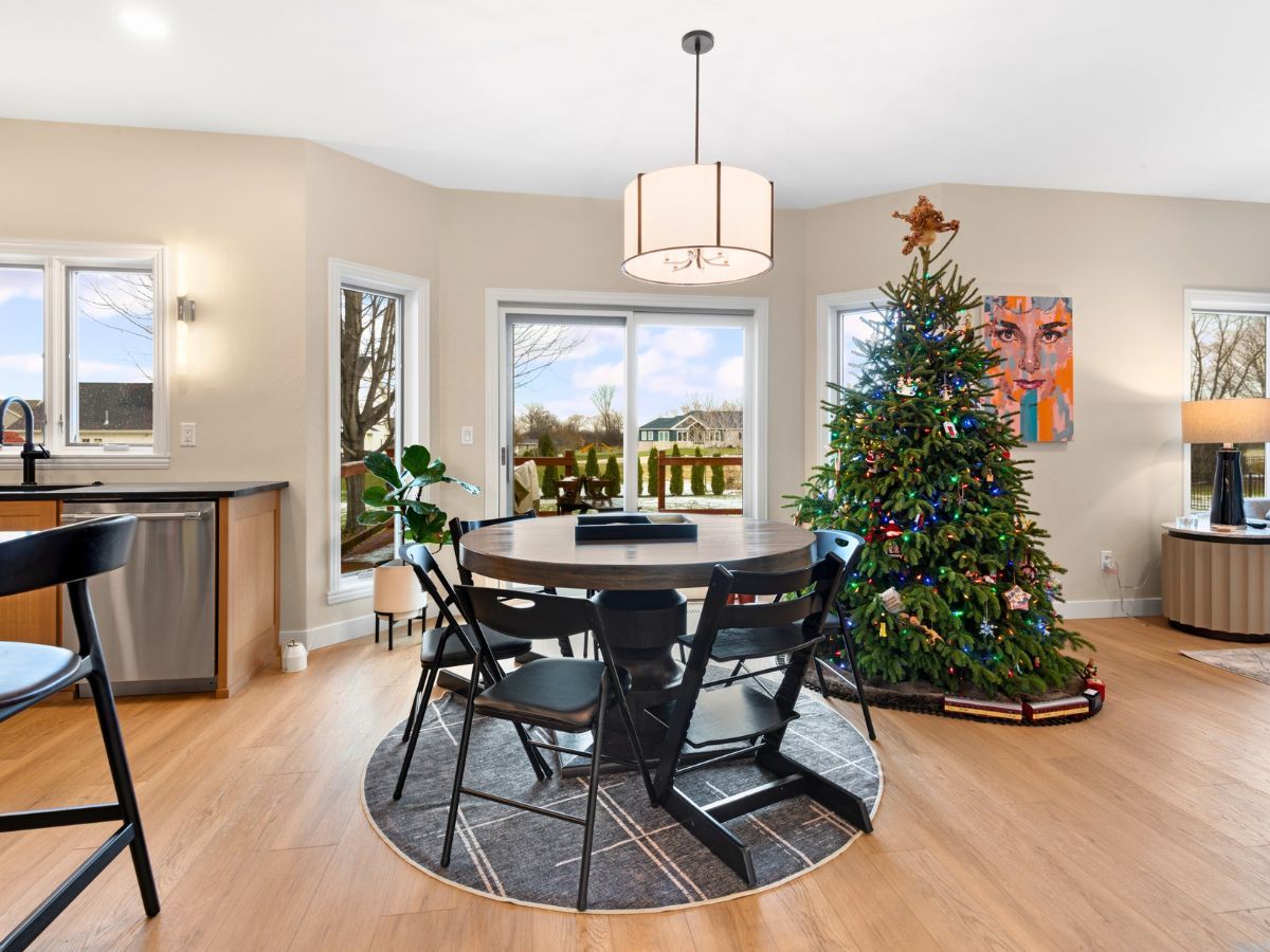 A dining room with a table and chairs and a christmas tree.