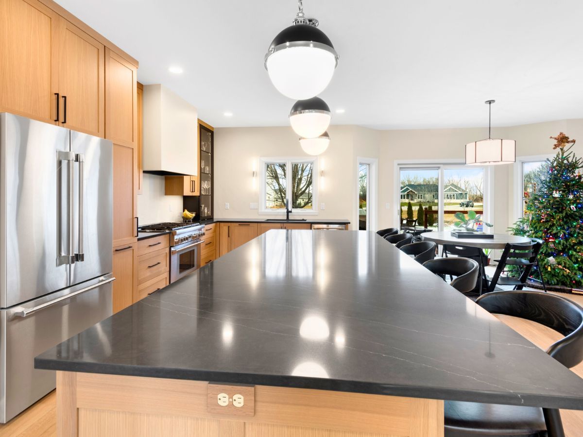 A kitchen with a large island and a christmas tree in the background.