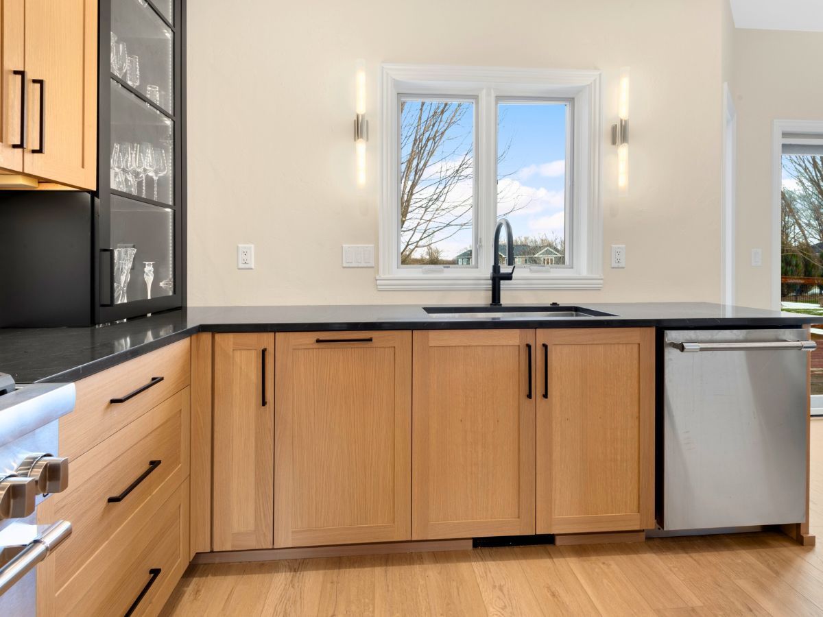A kitchen with wooden cabinets , a sink , and a window.