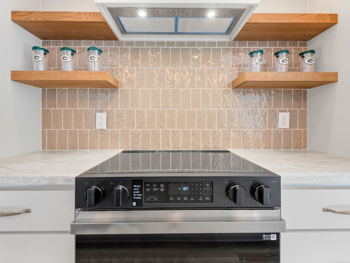 A kitchen with a stove , oven , and shelves.