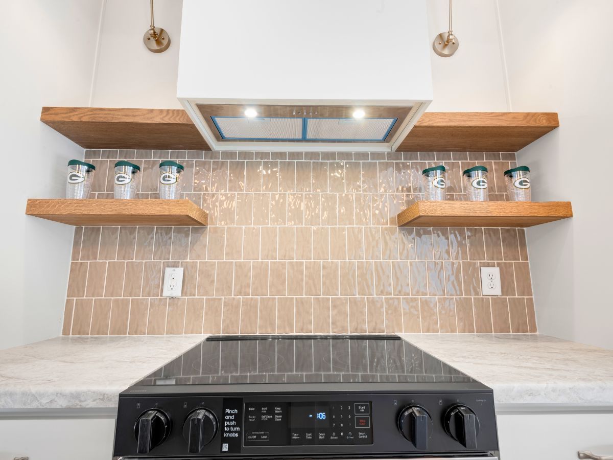 A kitchen with a stove top oven , shelves , and a hood.