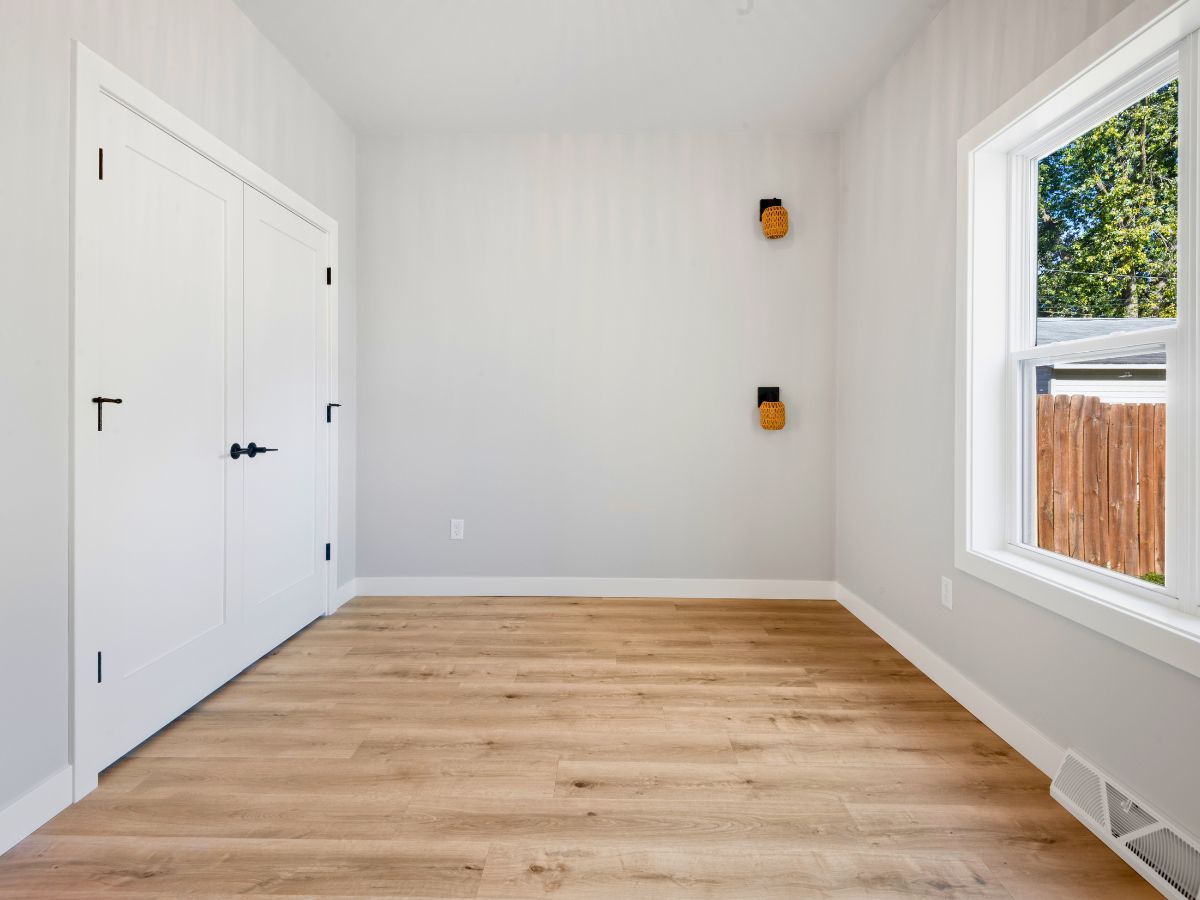 An empty room with hardwood floors and a window.