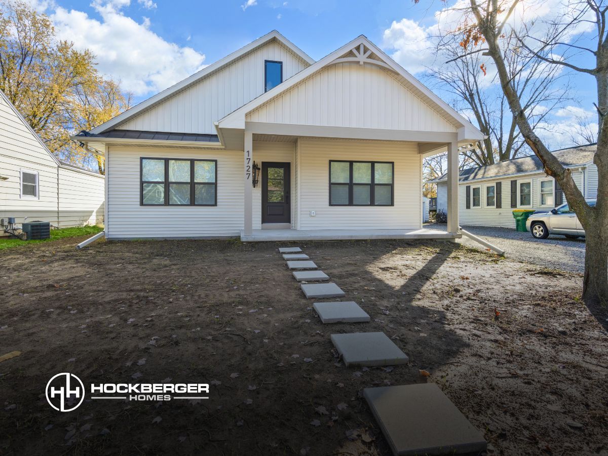 A white house with a black door and windows is for sale.