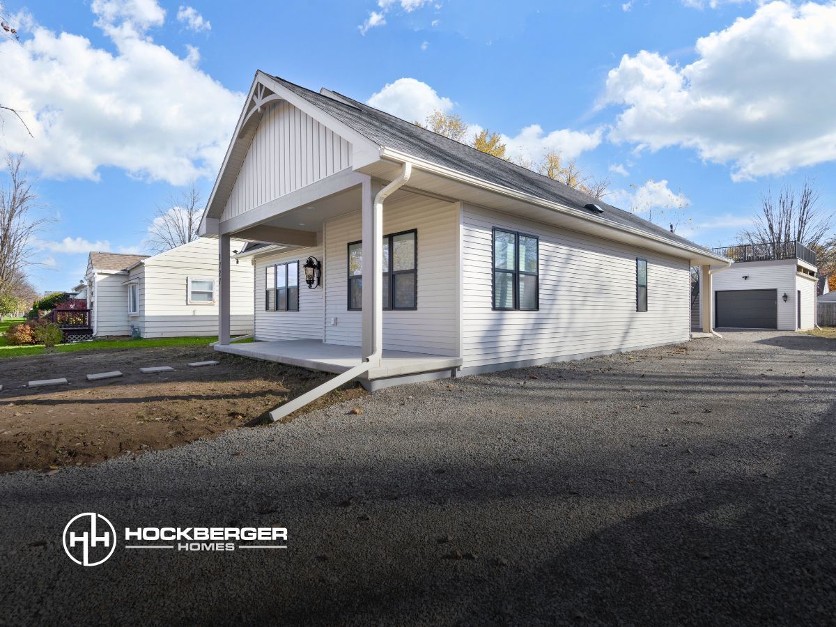 A white house with a porch and a garage is for sale.