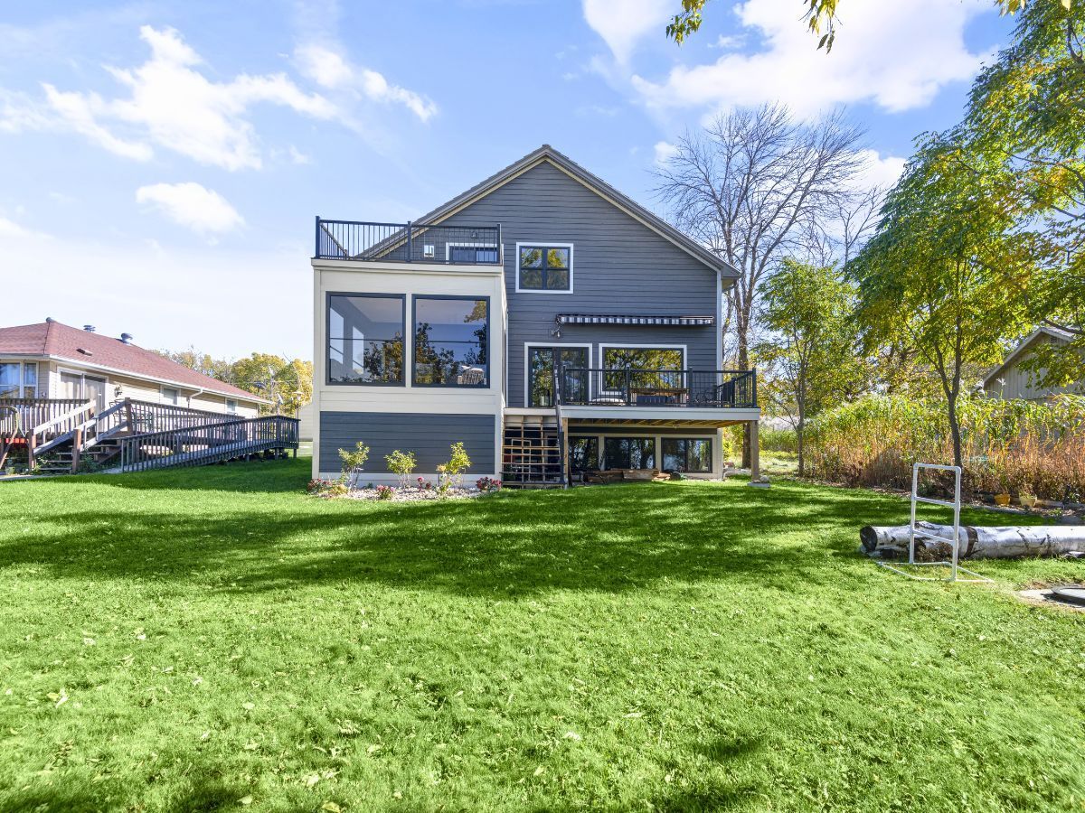 The back of a house with a large lawn in front of it.