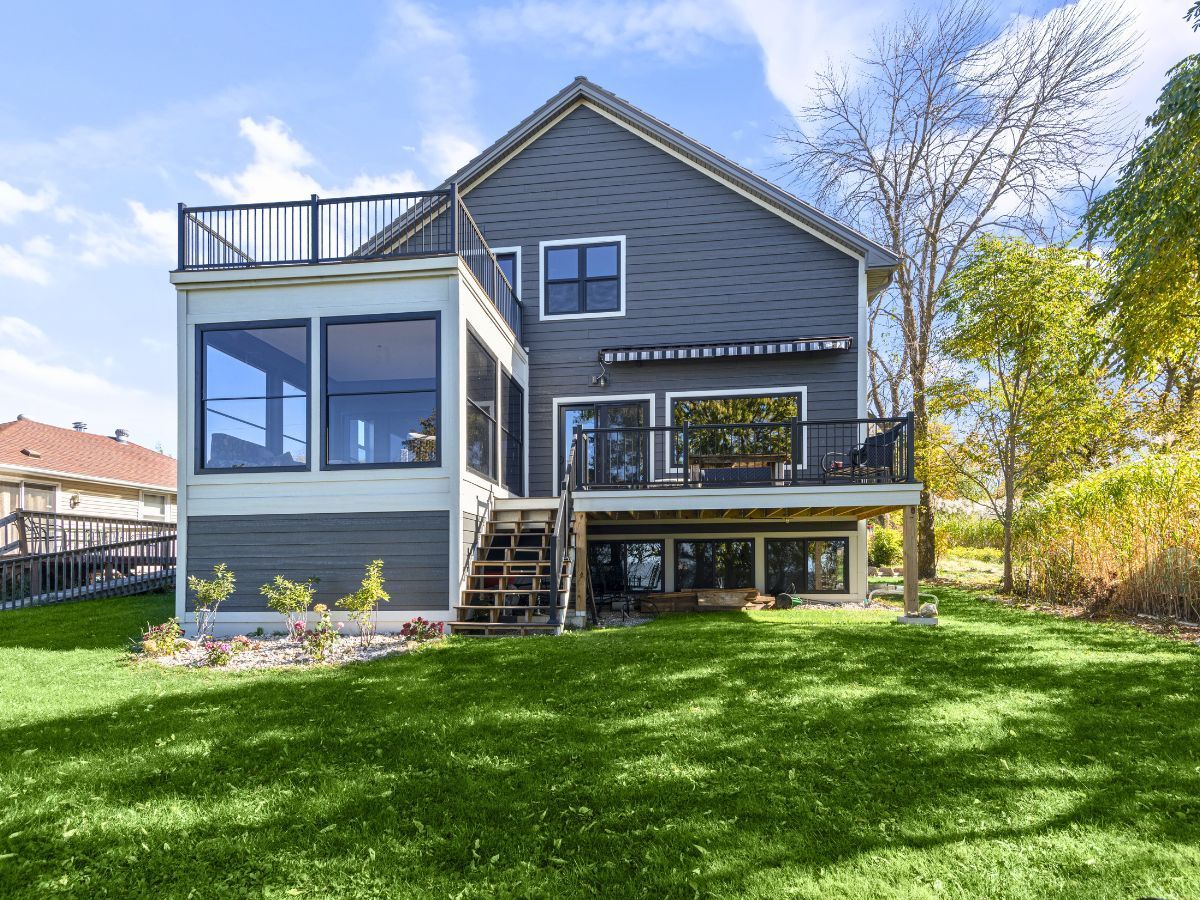 The back of a house with a large deck and a large lawn.
