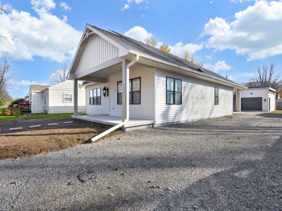 A white house with a porch and a garage is for sale.