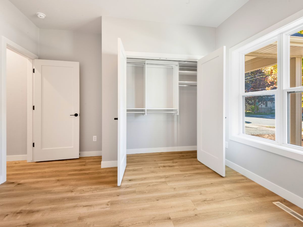 An empty bedroom with hardwood floors and a walk in closet.