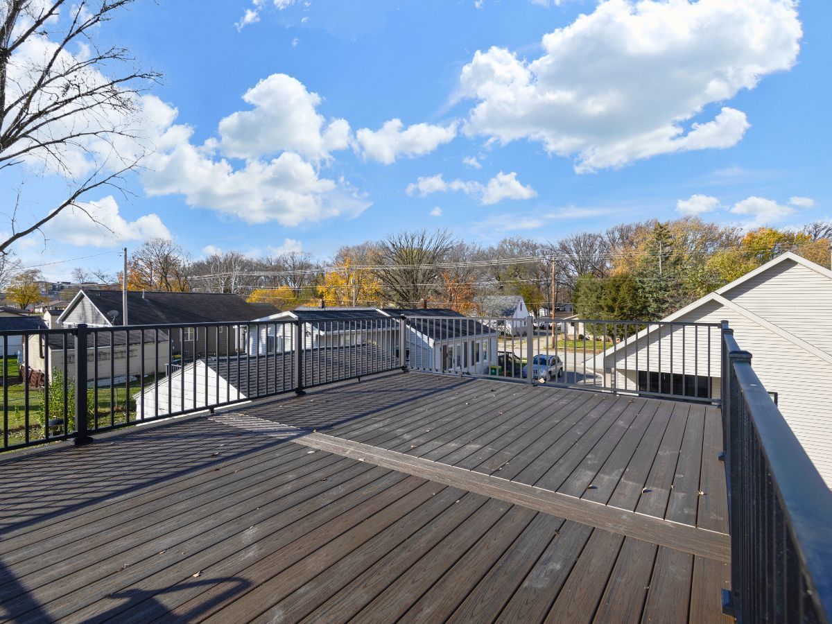 A large wooden deck with a railing and a view of a city.
