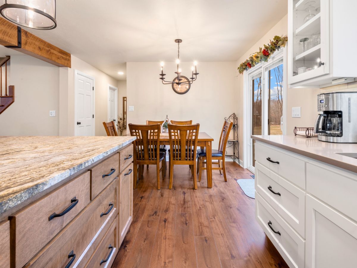 A kitchen with a dining room table and chairs in the background.