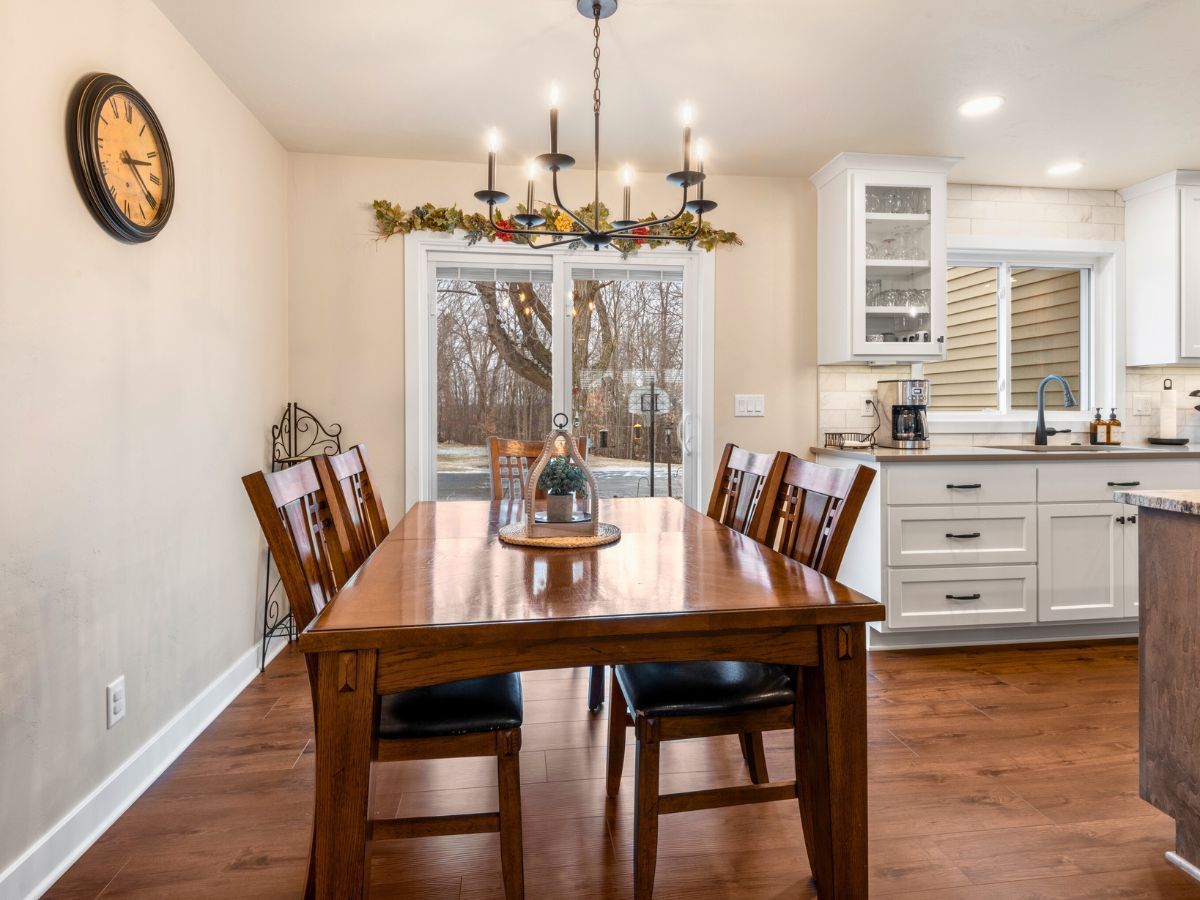 A dining room with a table and chairs and a clock on the wall