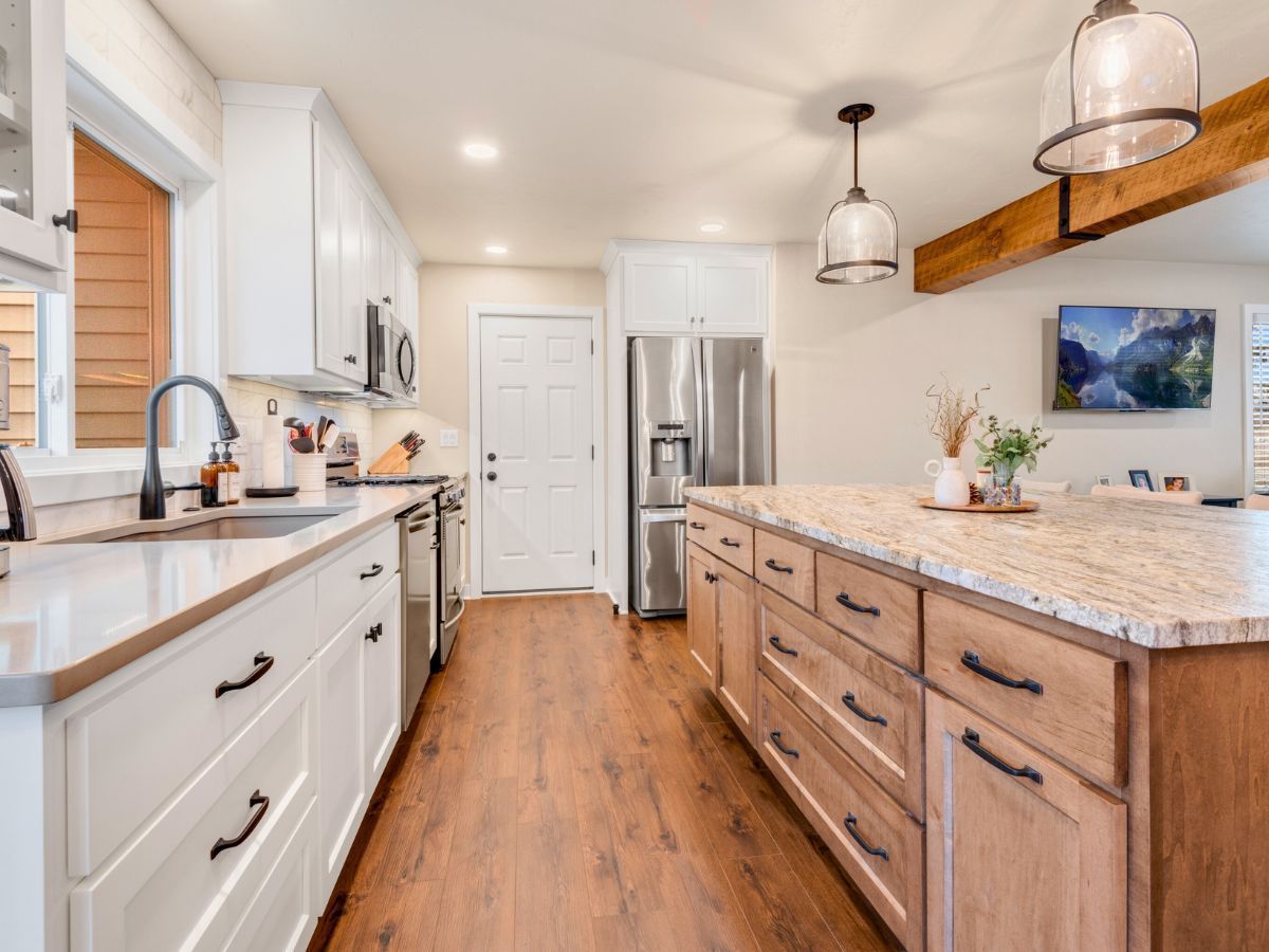 A kitchen with white cabinets , granite counter tops , stainless steel appliances and a large island.