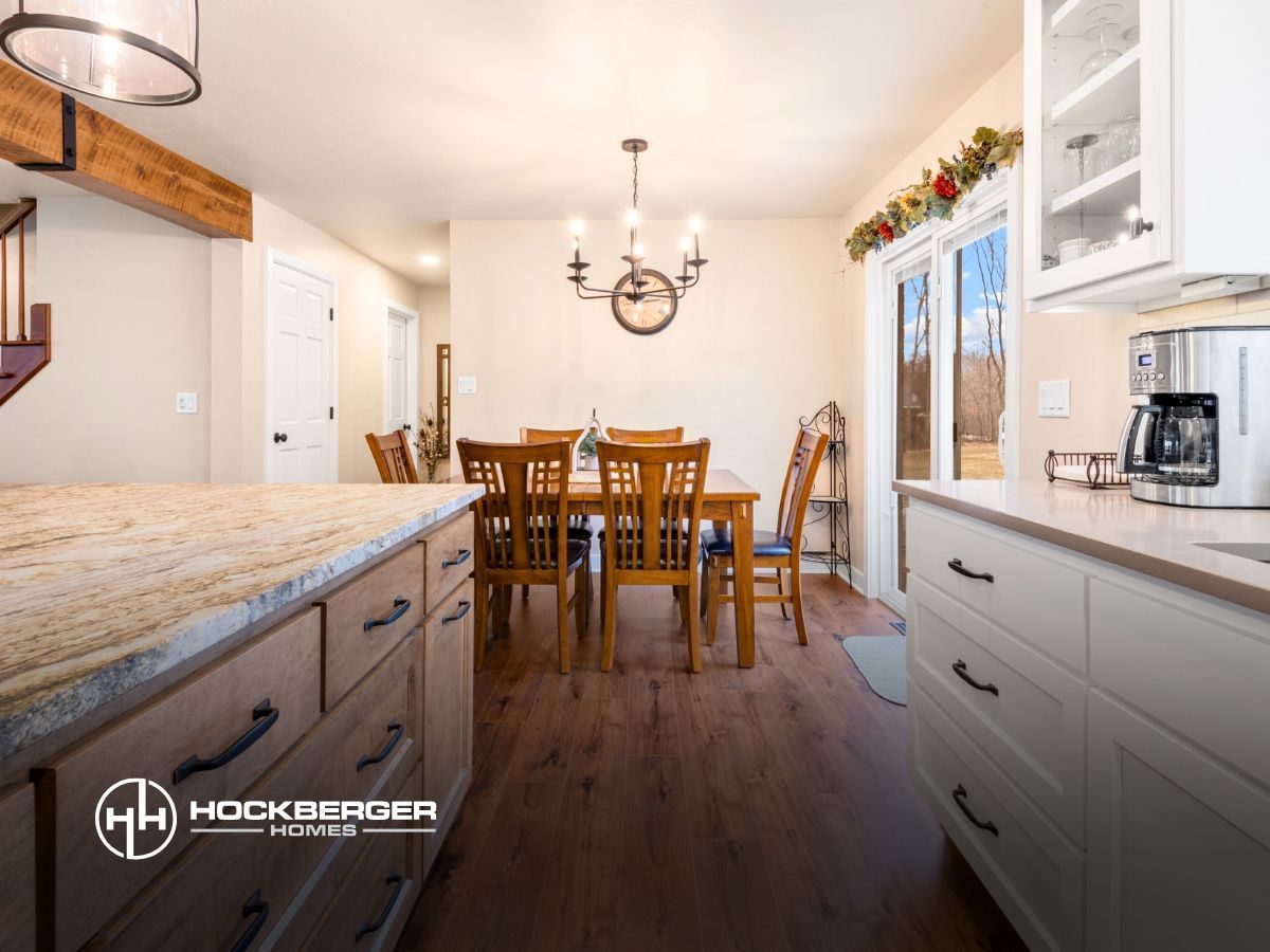 A kitchen with a dining room table and chairs in the background.