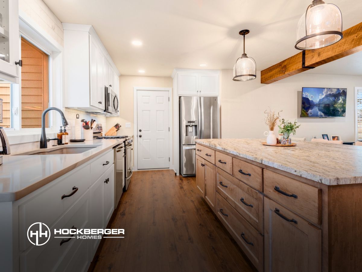 A kitchen with white cabinets , granite counter tops , stainless steel appliances and a large island.