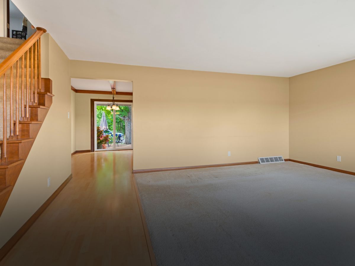 An empty living room with hardwood floors and a staircase leading to the second floor.
