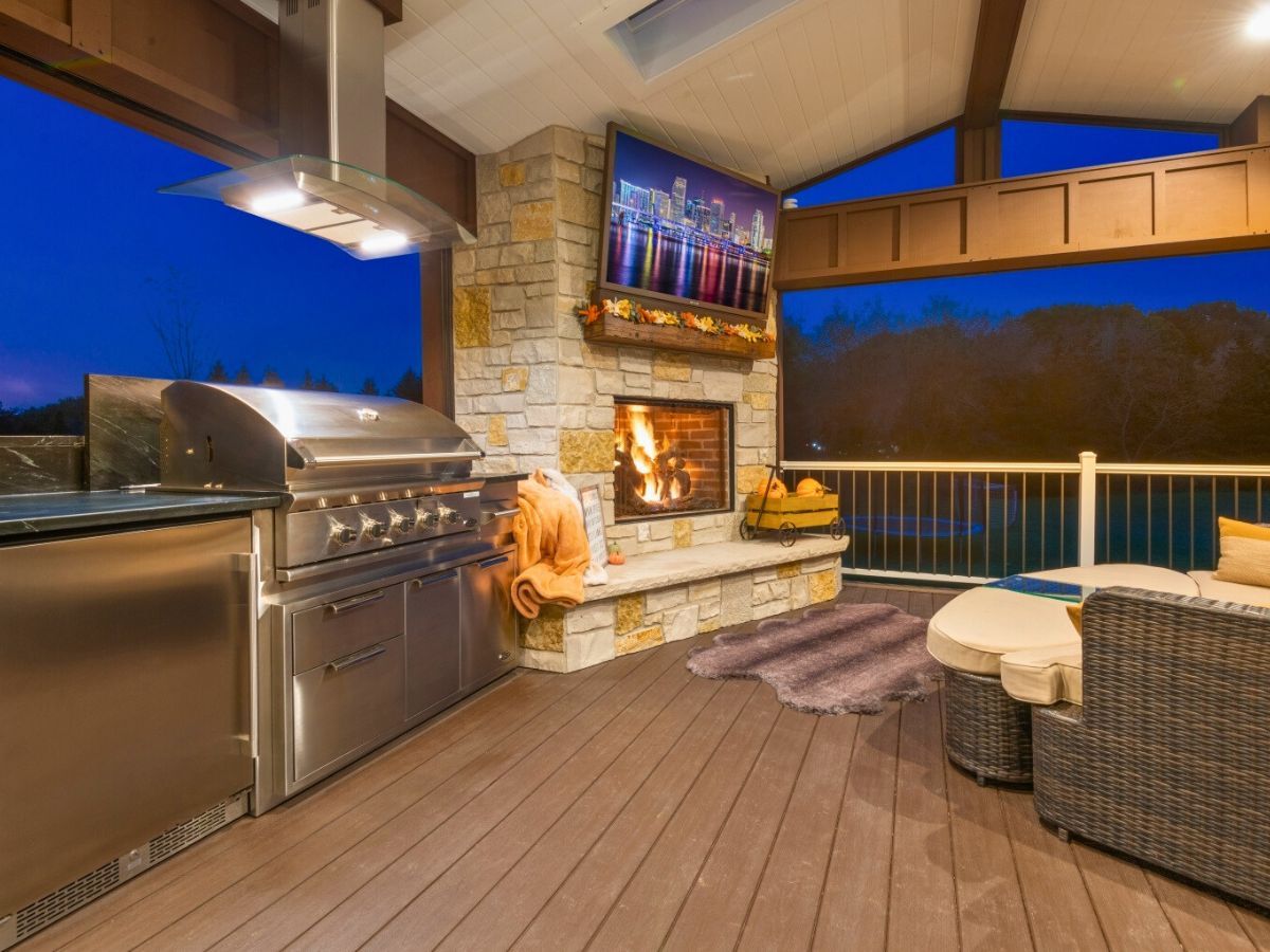A patio with a fireplace and a stainless steel grill.