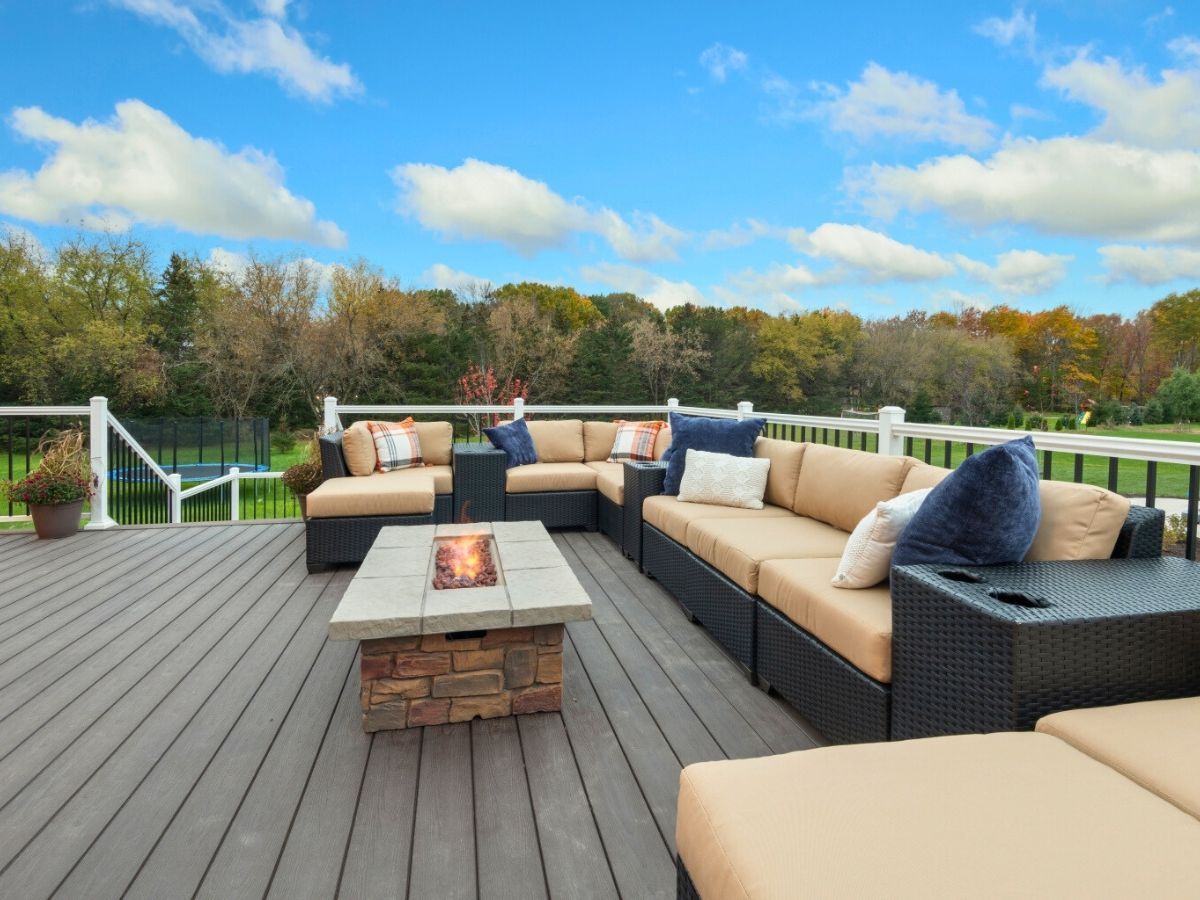 There is a fire pit on the deck with a lot of furniture on it.