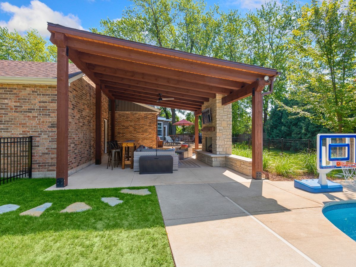A backyard with a covered patio and a pool.