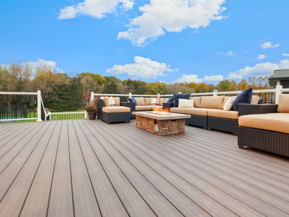 There is a fire pit on the deck with a lot of furniture on it.