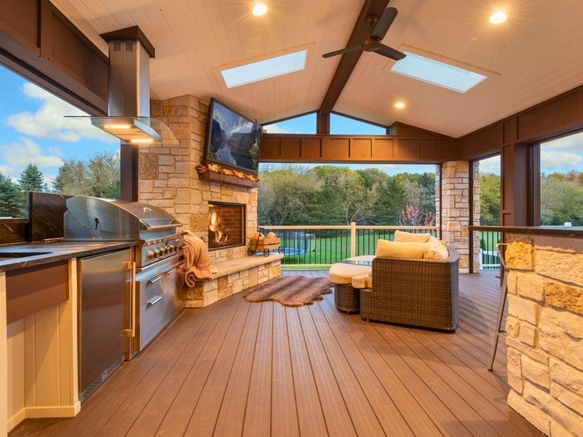 A large deck with a fireplace and a ceiling fan.
