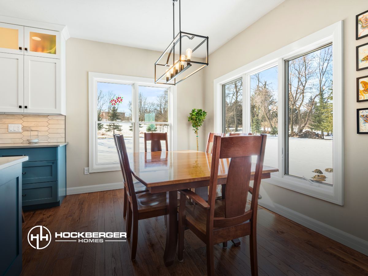 A dining room with a table and chairs and a lot of windows.