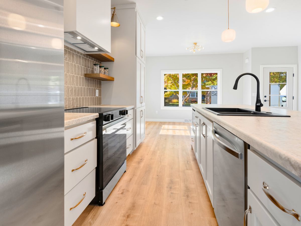 A kitchen with stainless steel appliances and wooden floors.