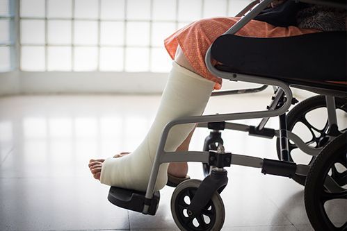 Leg in a white cast resting on a wheelchair footrest indoors