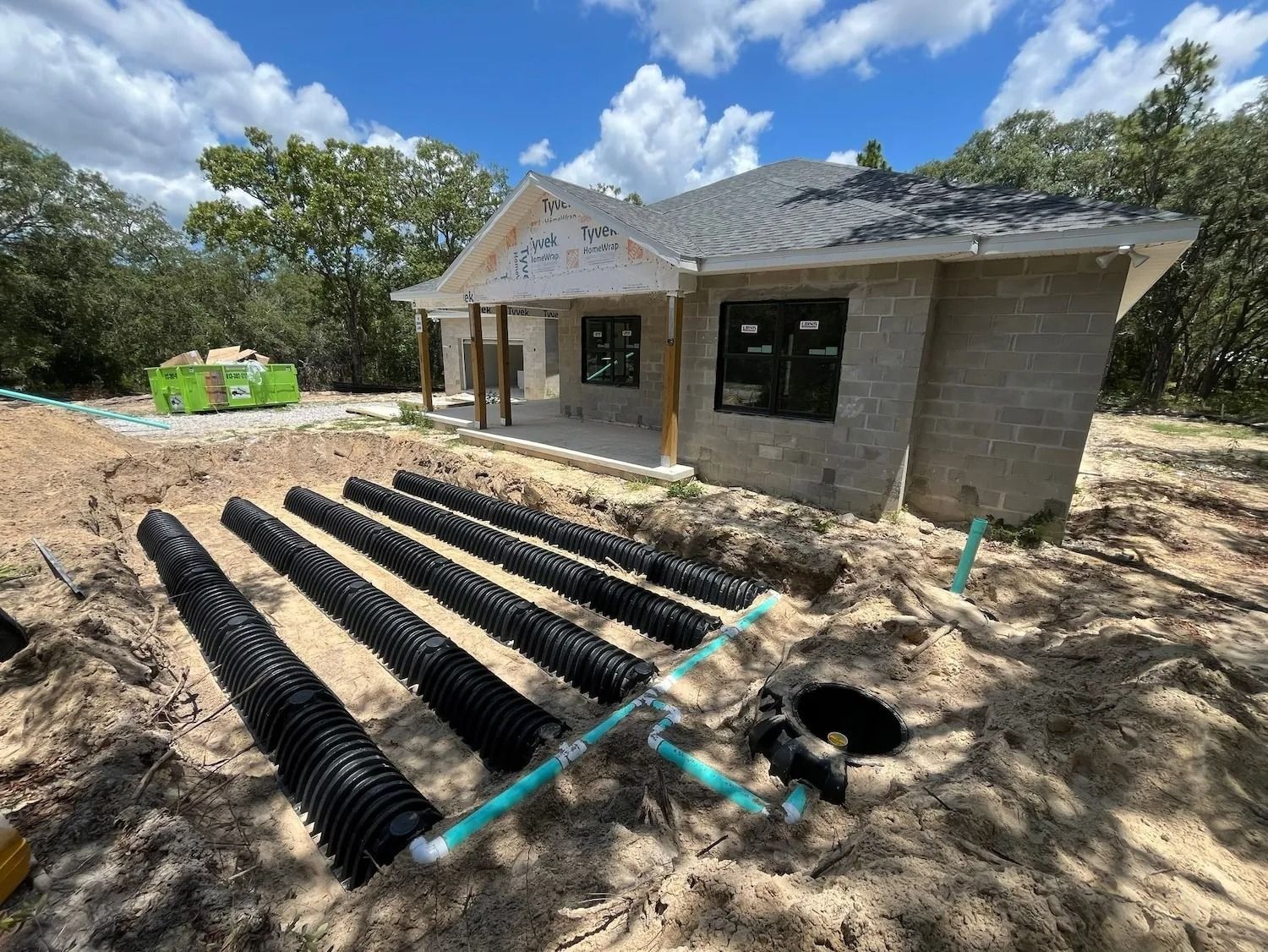 House under construction with drainage pipes and dirt yard in front