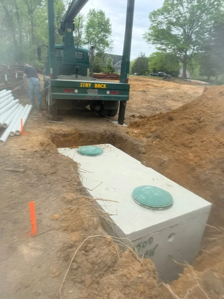 Construction site with excavator beside a large concrete utility box in a dirt trench