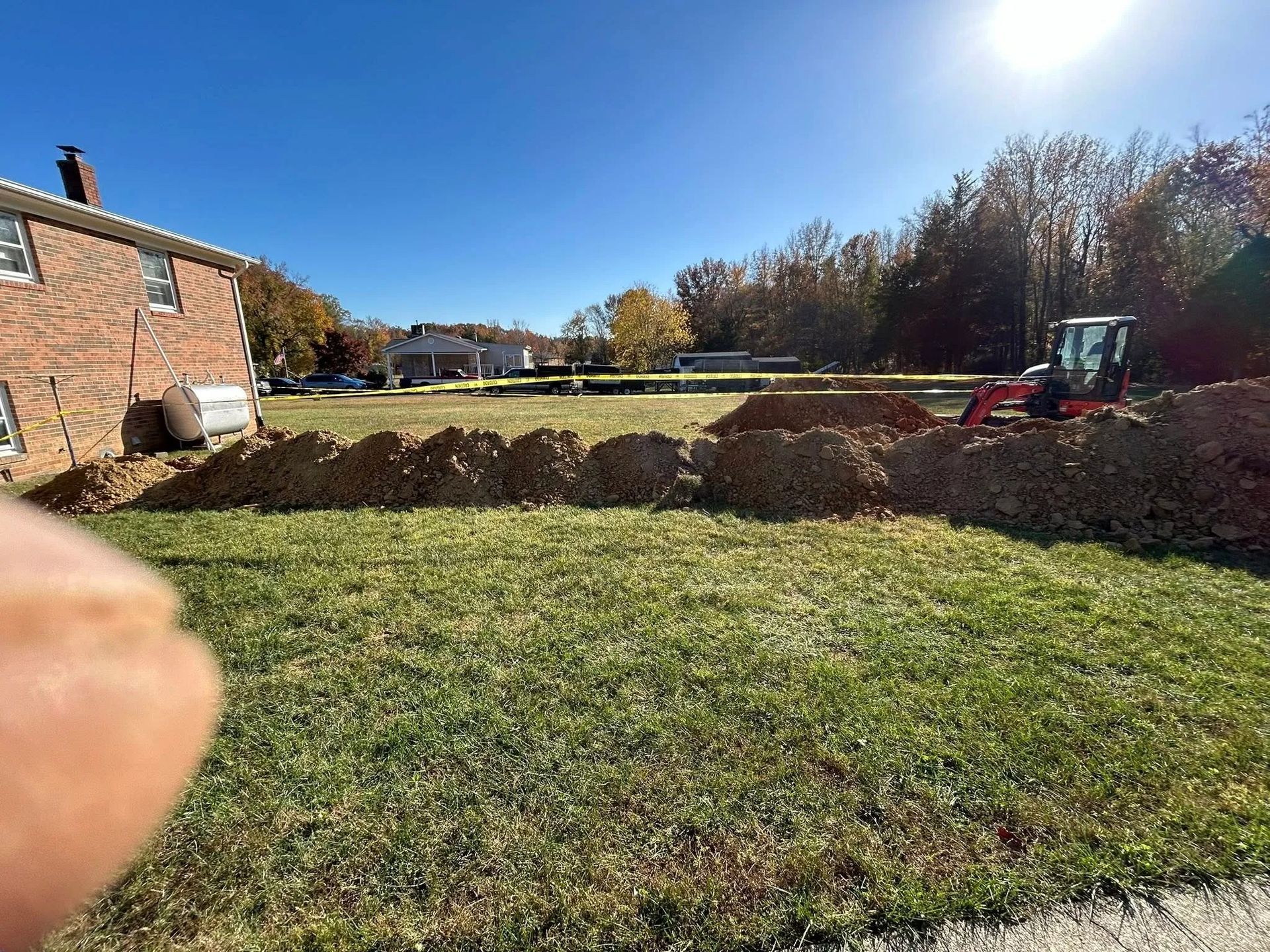 Grassy backyard with brick house, raised garden beds, autumn trees, and a bright sunny sky