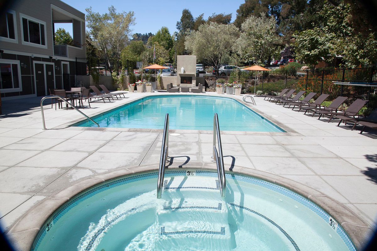 Outdoor community pool area with lounge chairs and a central outdoor fireplace.
