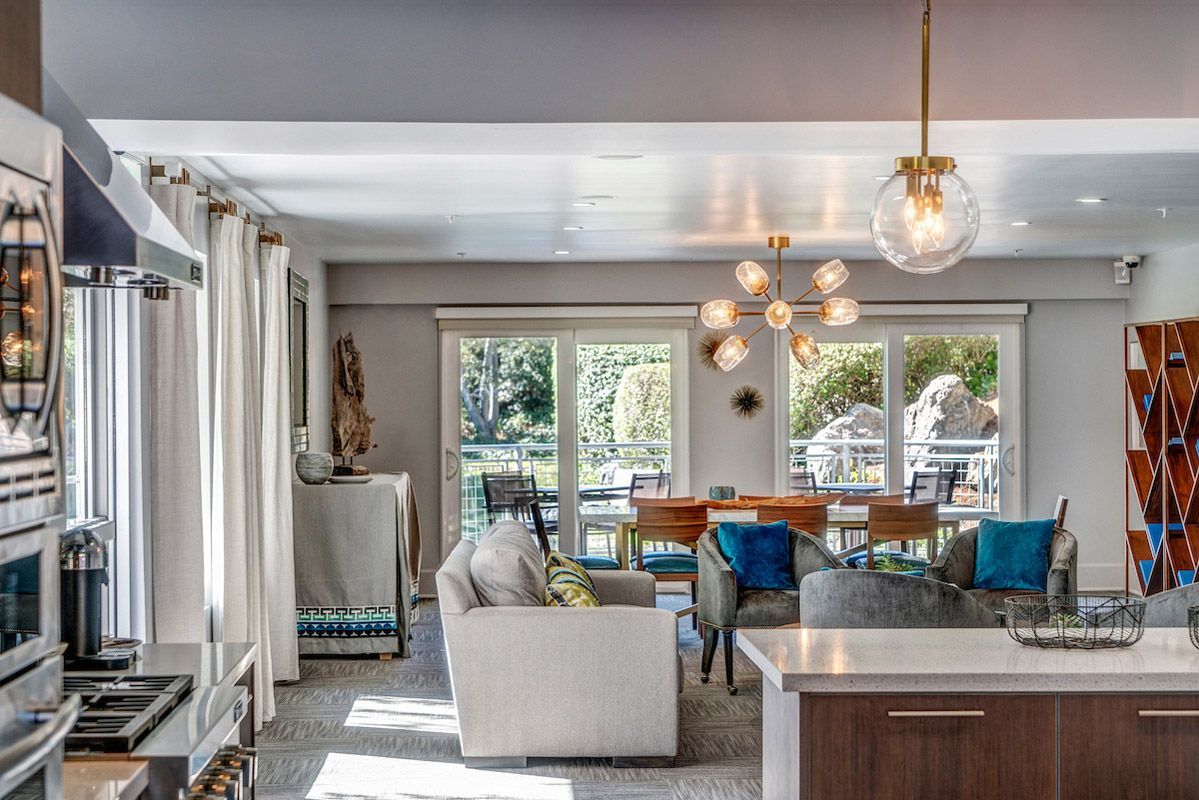 Open-concept living area with kitchen island, seating, and dining table by glass doors to a balcony.