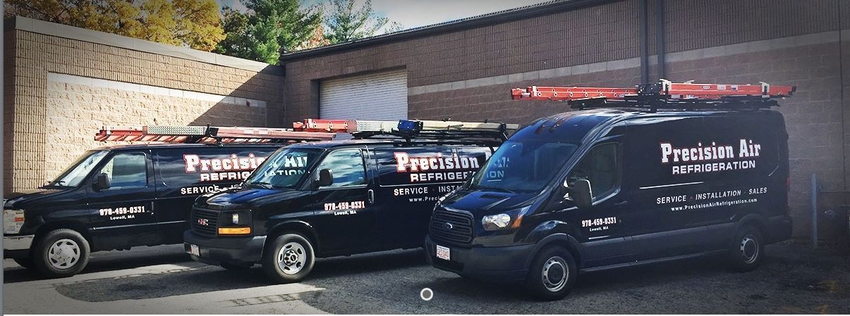 Three black vans are parked in front of a building.