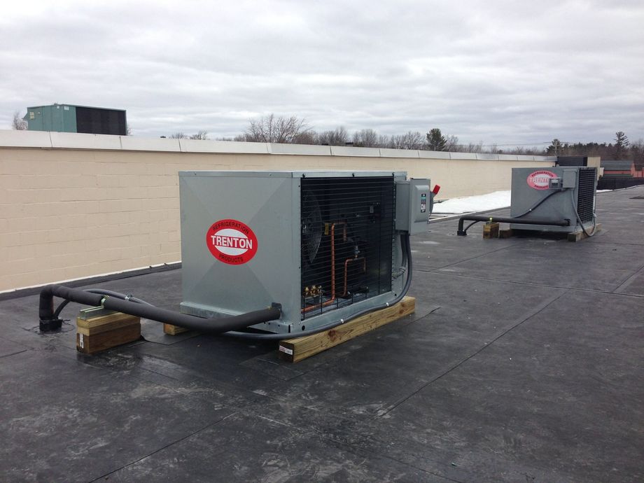 Two air conditioners are sitting on top of a roof.