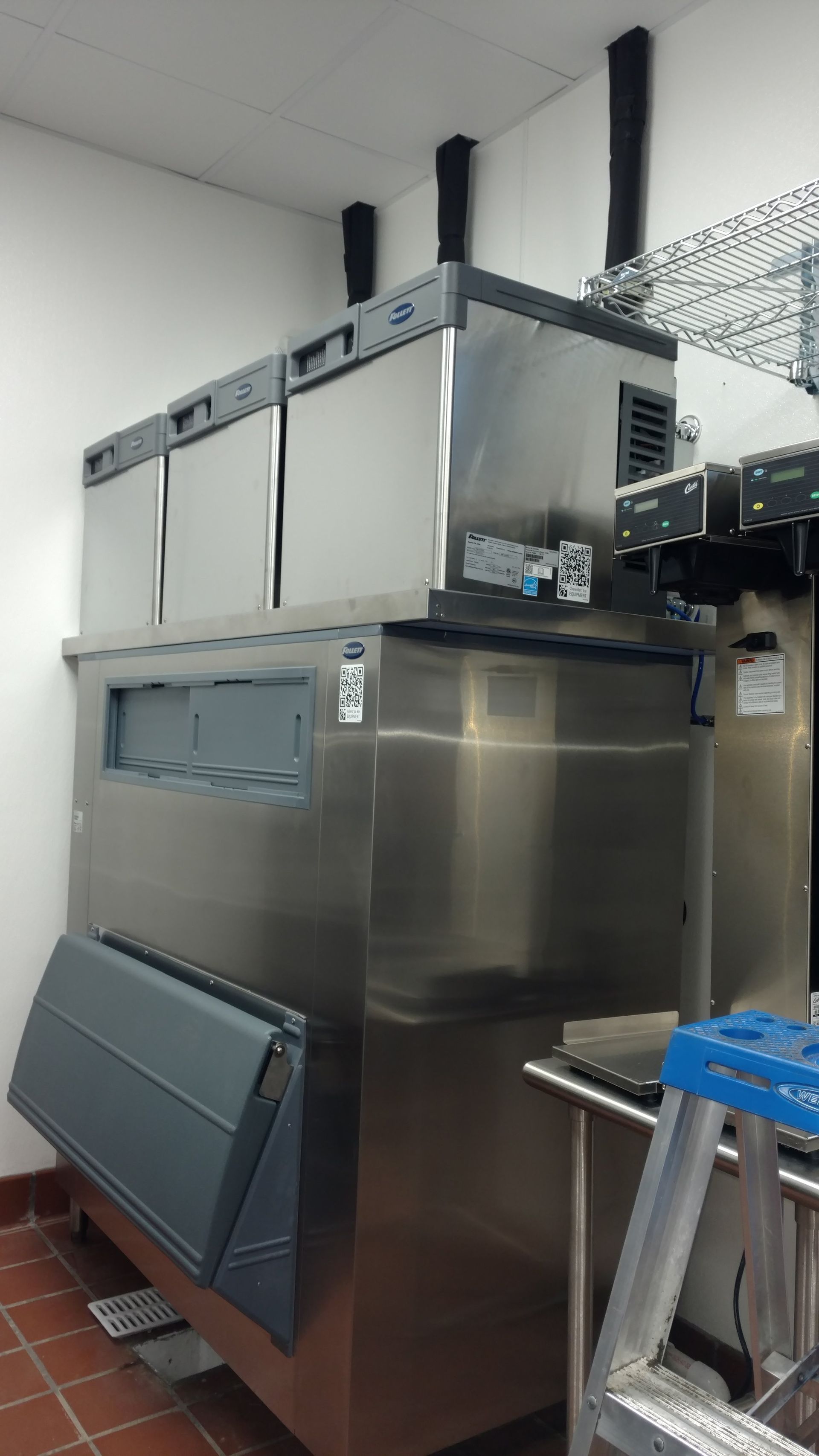 A large stainless steel refrigerator is sitting in a kitchen next to a ladder.