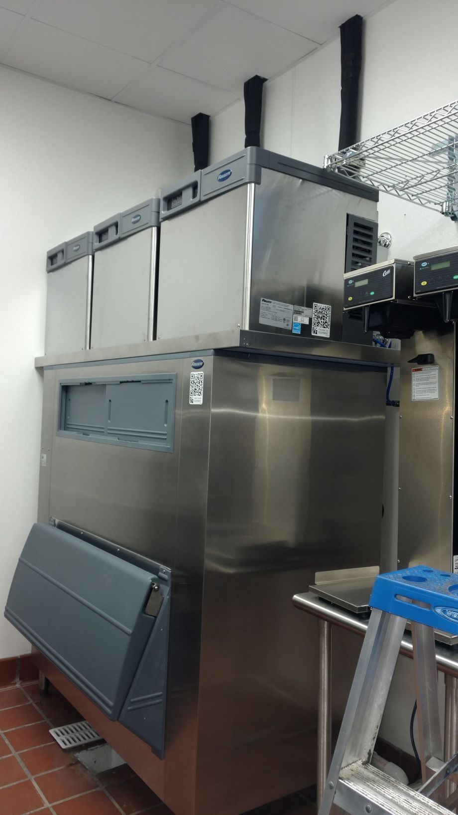 A large stainless steel refrigerator is sitting in a kitchen next to a ladder.